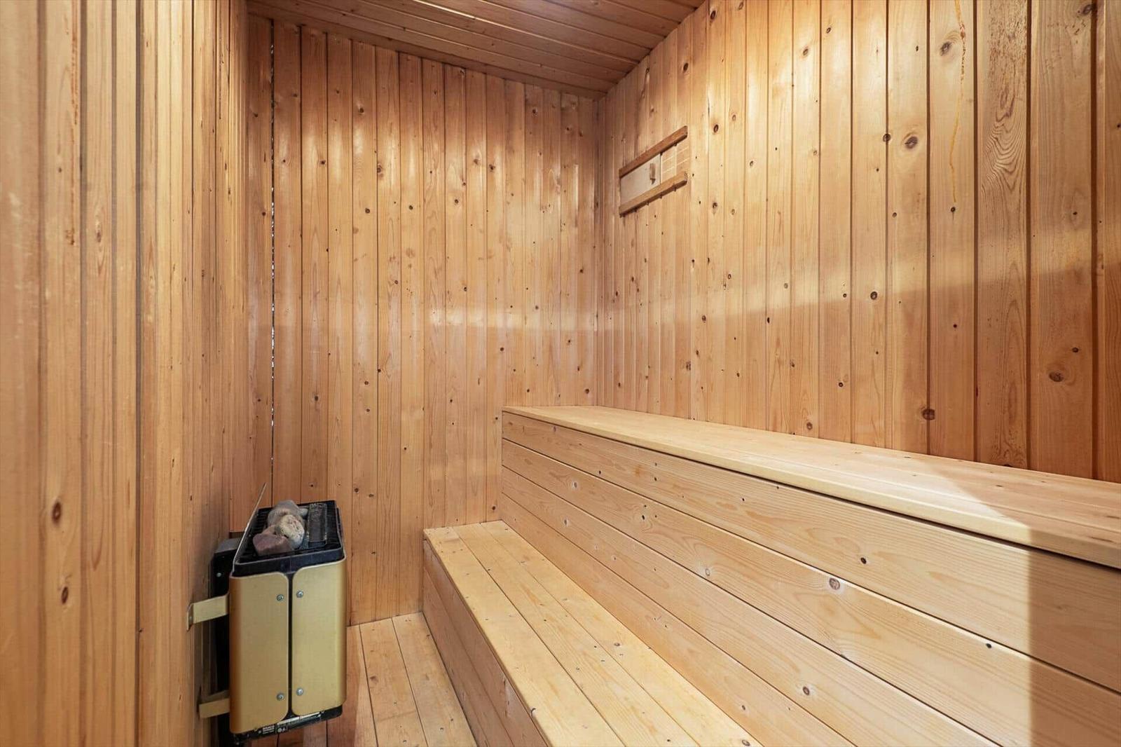 Sauna mit Holzwand und Sitzbank, Heizgerät an der Wand.