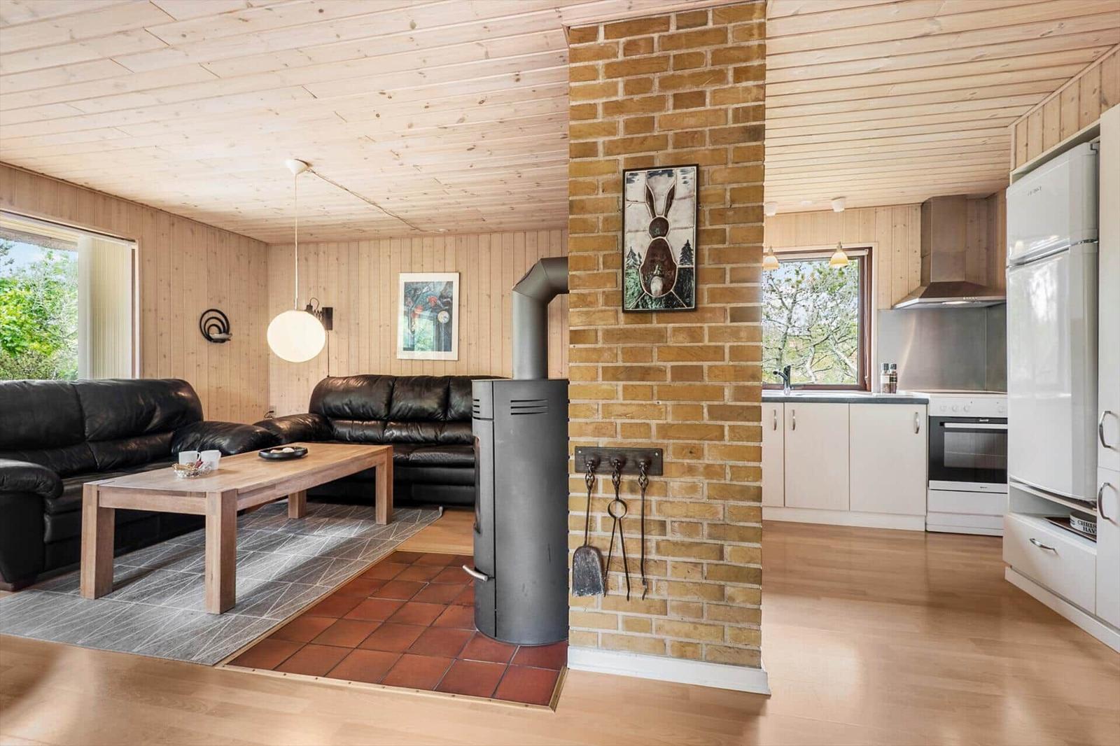 Wohnzimmer mit Sofa, Kamin und Küche im Hintergrund.