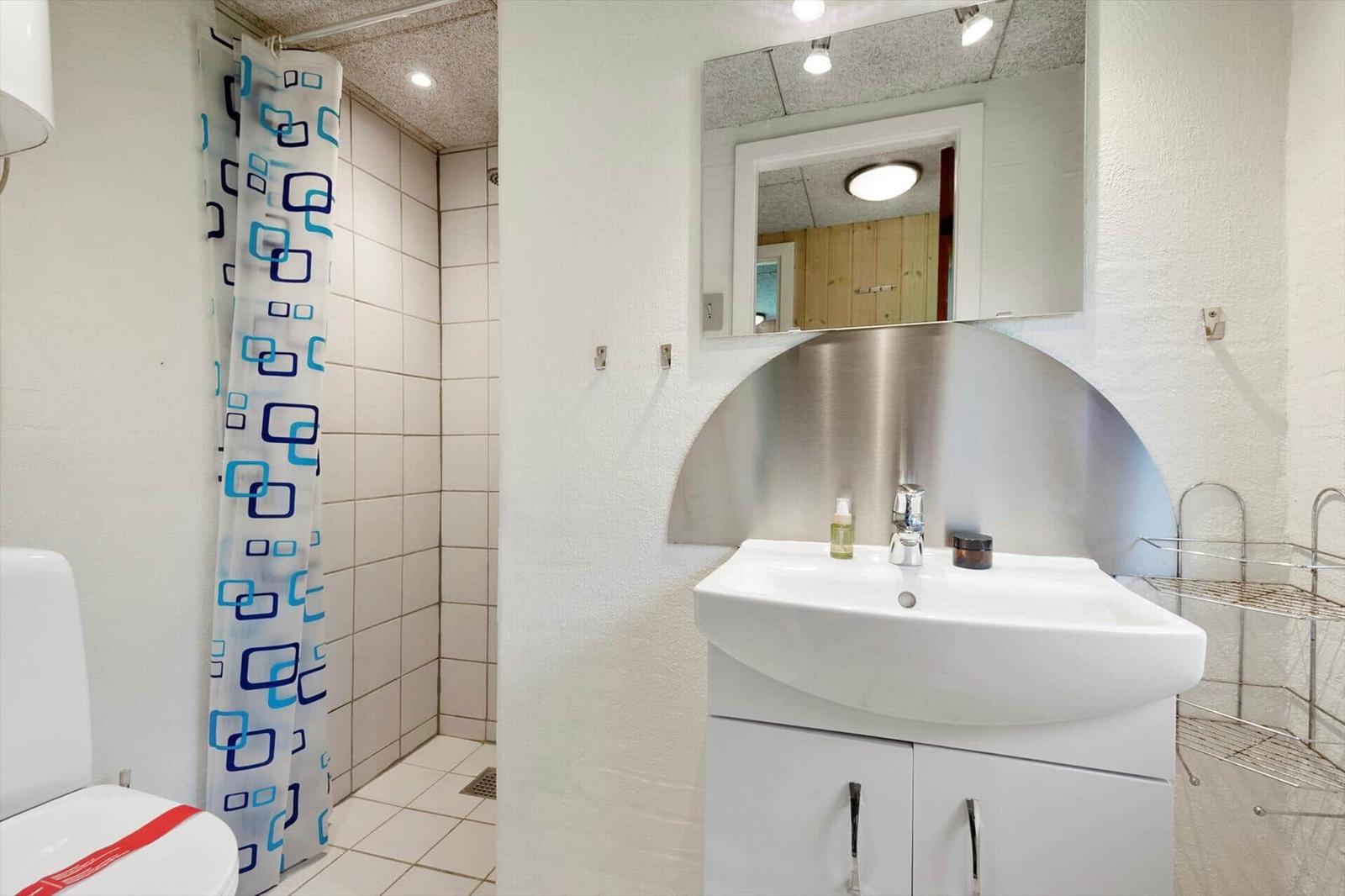 Badezimmer mit Dusche, Waschbecken und Spiegel.