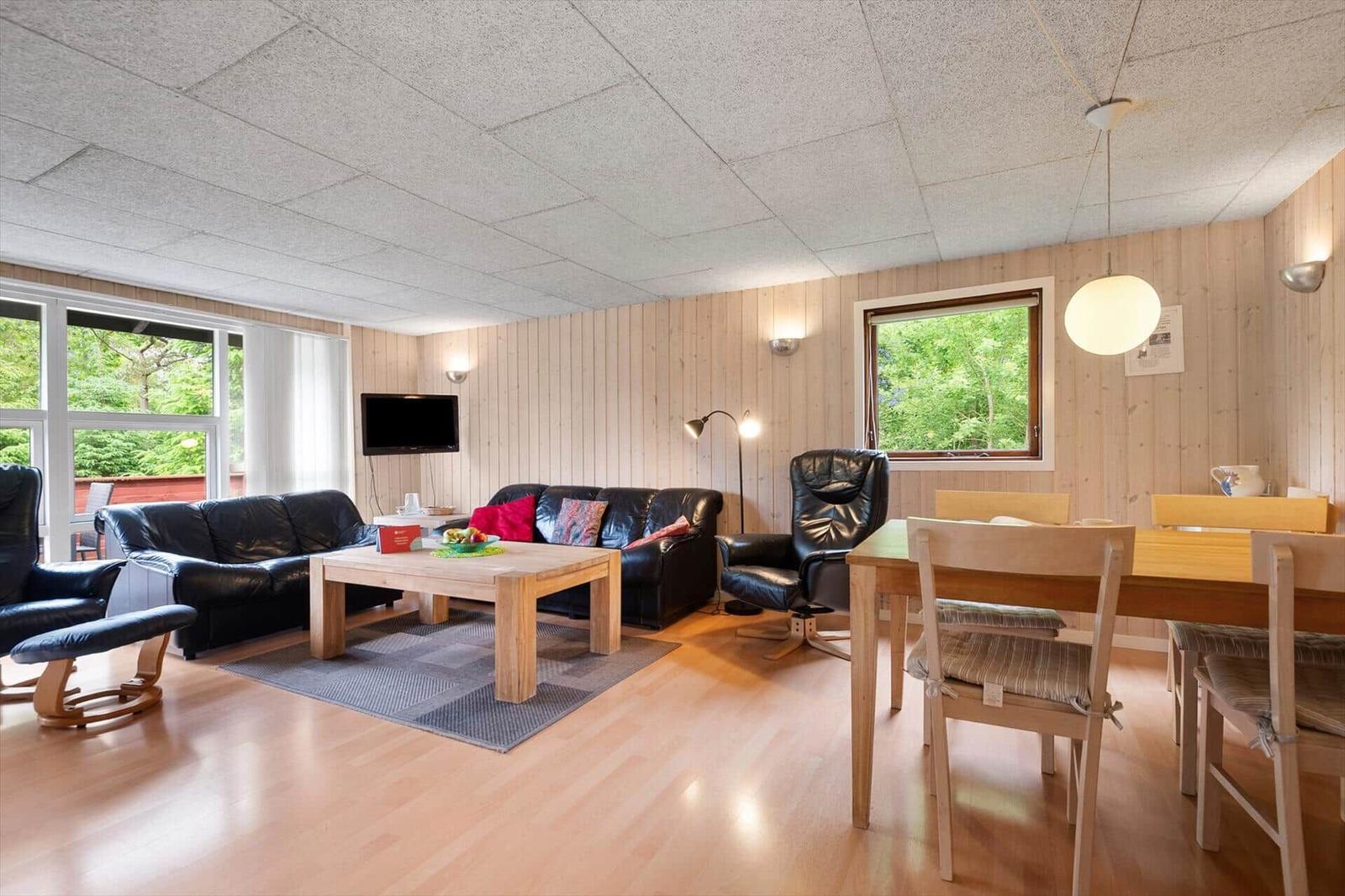 Wohn- und Essbereich mit Sofa, Esstisch und Fenstern.
