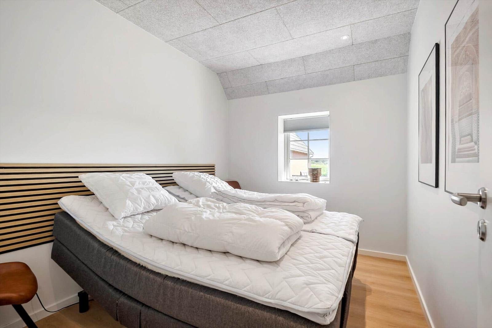 Schlafzimmer mit Bett, Fenster und Holzboden.