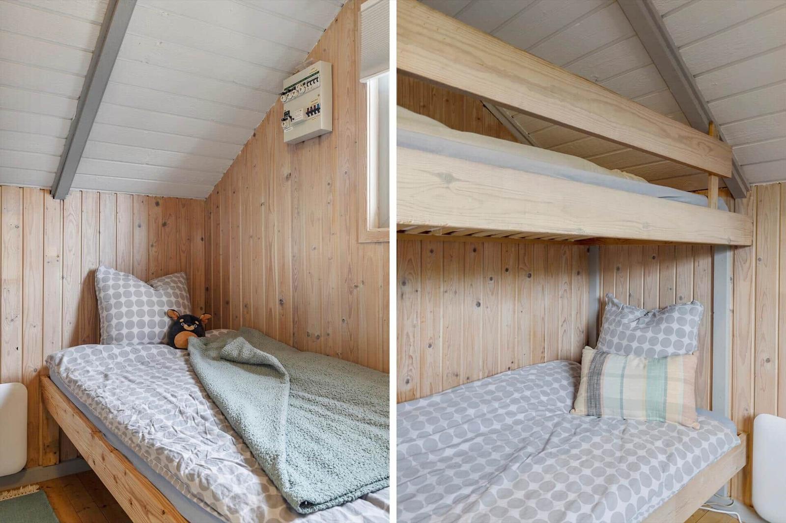 Zimmer mit Holzwand und Doppelbett. Ein Bett ist unter dem anderen angebracht.
