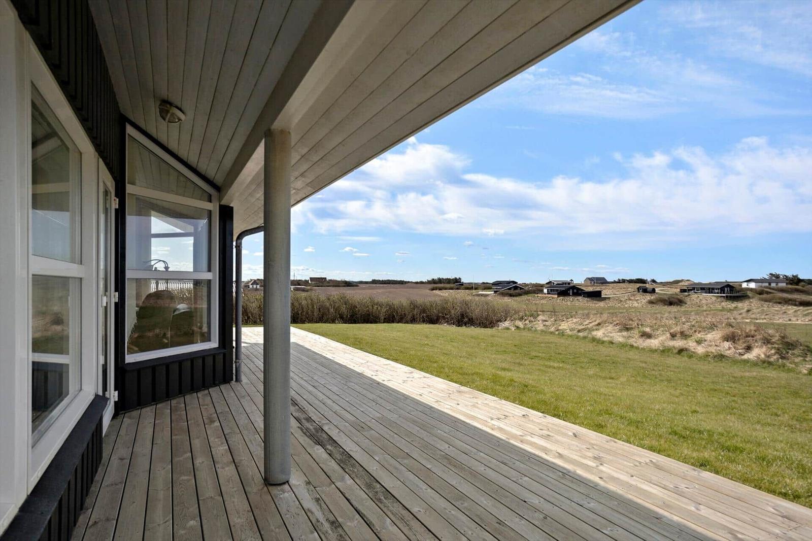 Terrasse mit Holzboden und Sicht auf Grasland und Häuser im Hintergrund.