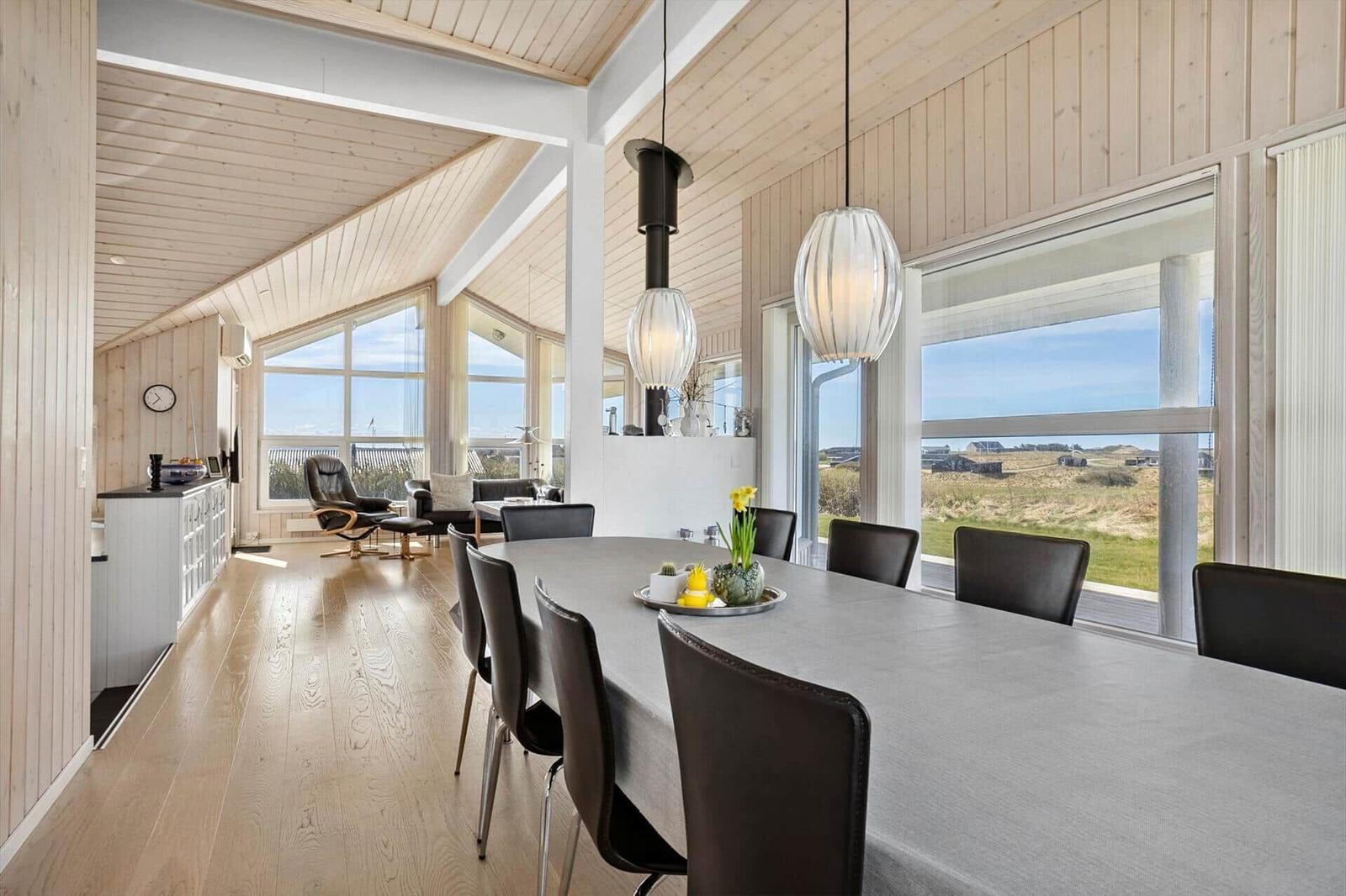 Essbereich mit Tisch und Stühlen, große Fenster mit Blick auf Landschaft.