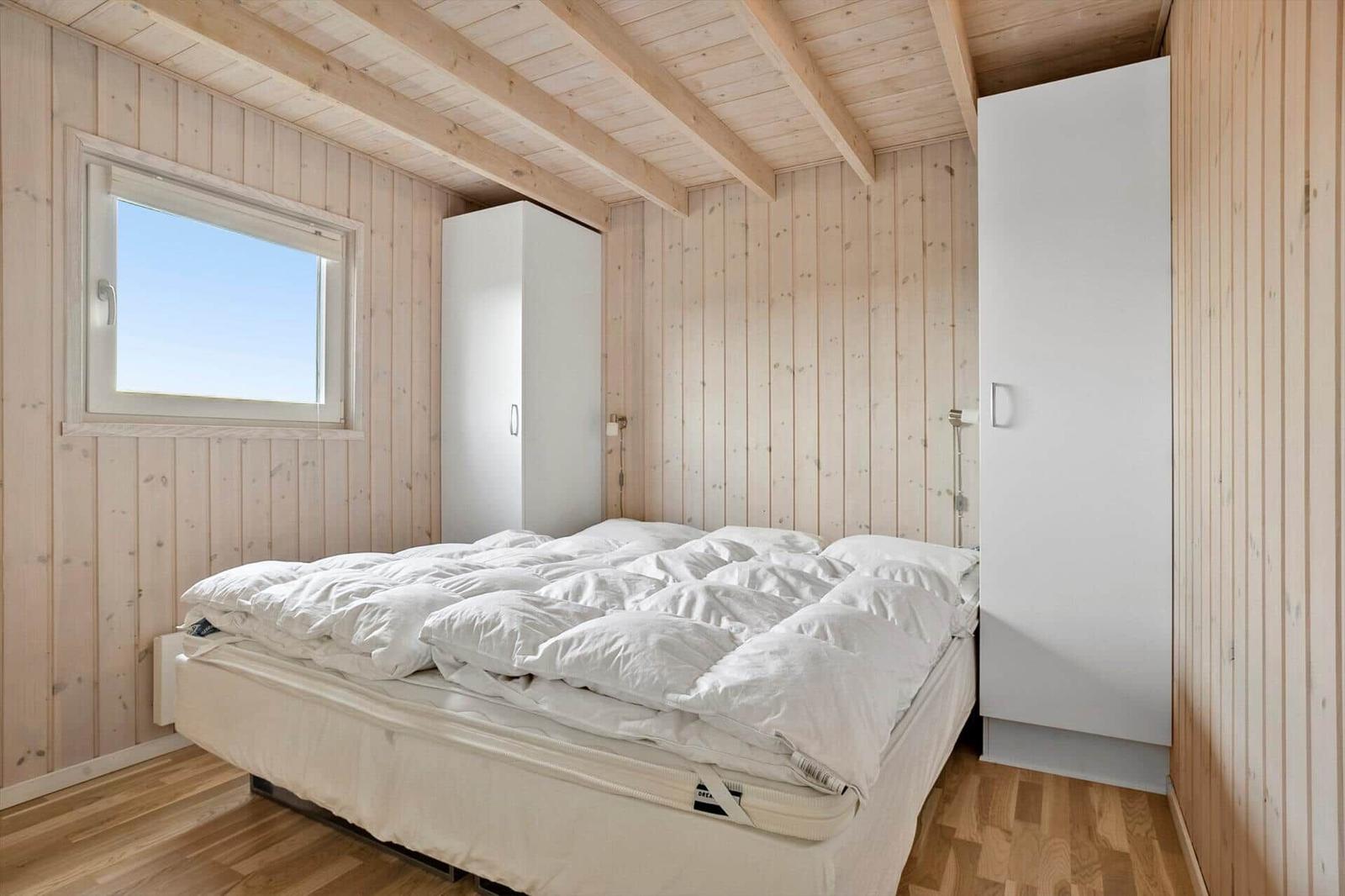Schlafzimmer mit Holzwänden, Bett und Fenster