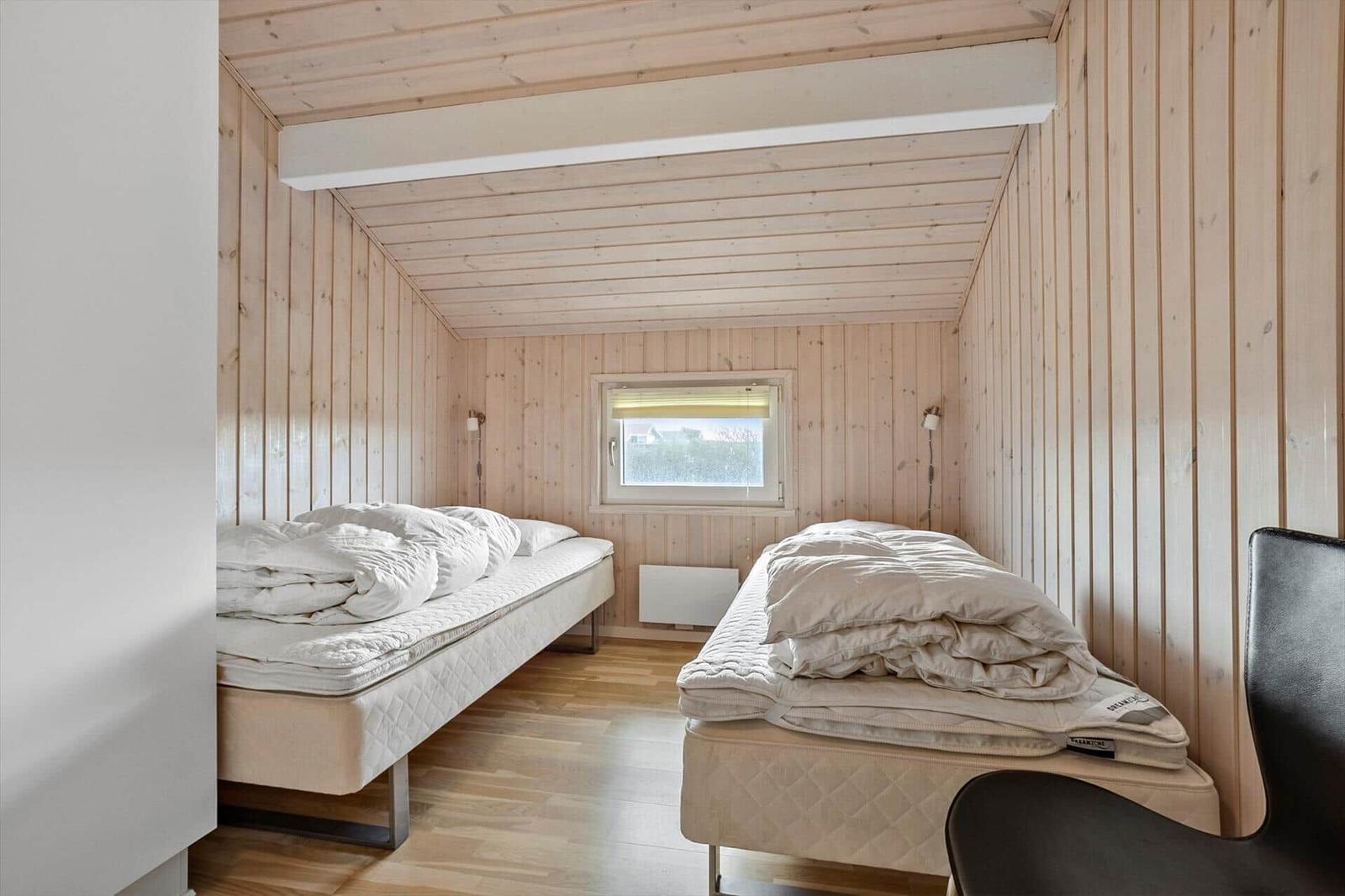 Zwei Betten in einem Raum mit Holzwänden und einem Fenster.