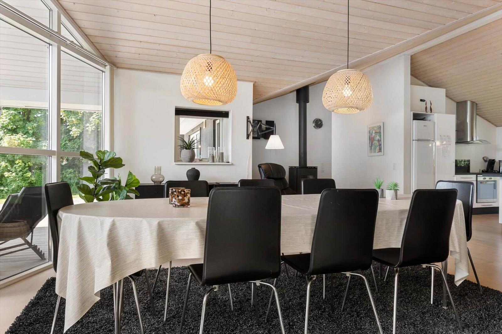 Essbereich mit runder Tafel, schwarzen Stühlen und zwei hängenden Lampen.