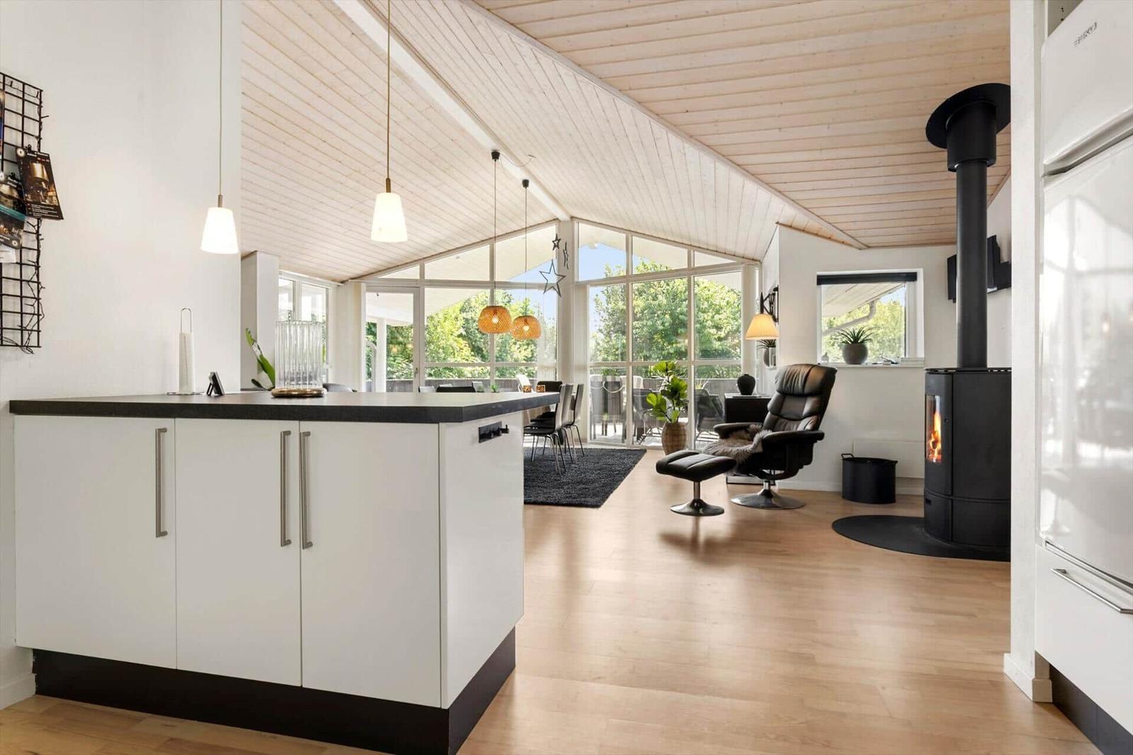 Küche mit Insel, Wohnbereich mit Kamin und großem Fensterblick.