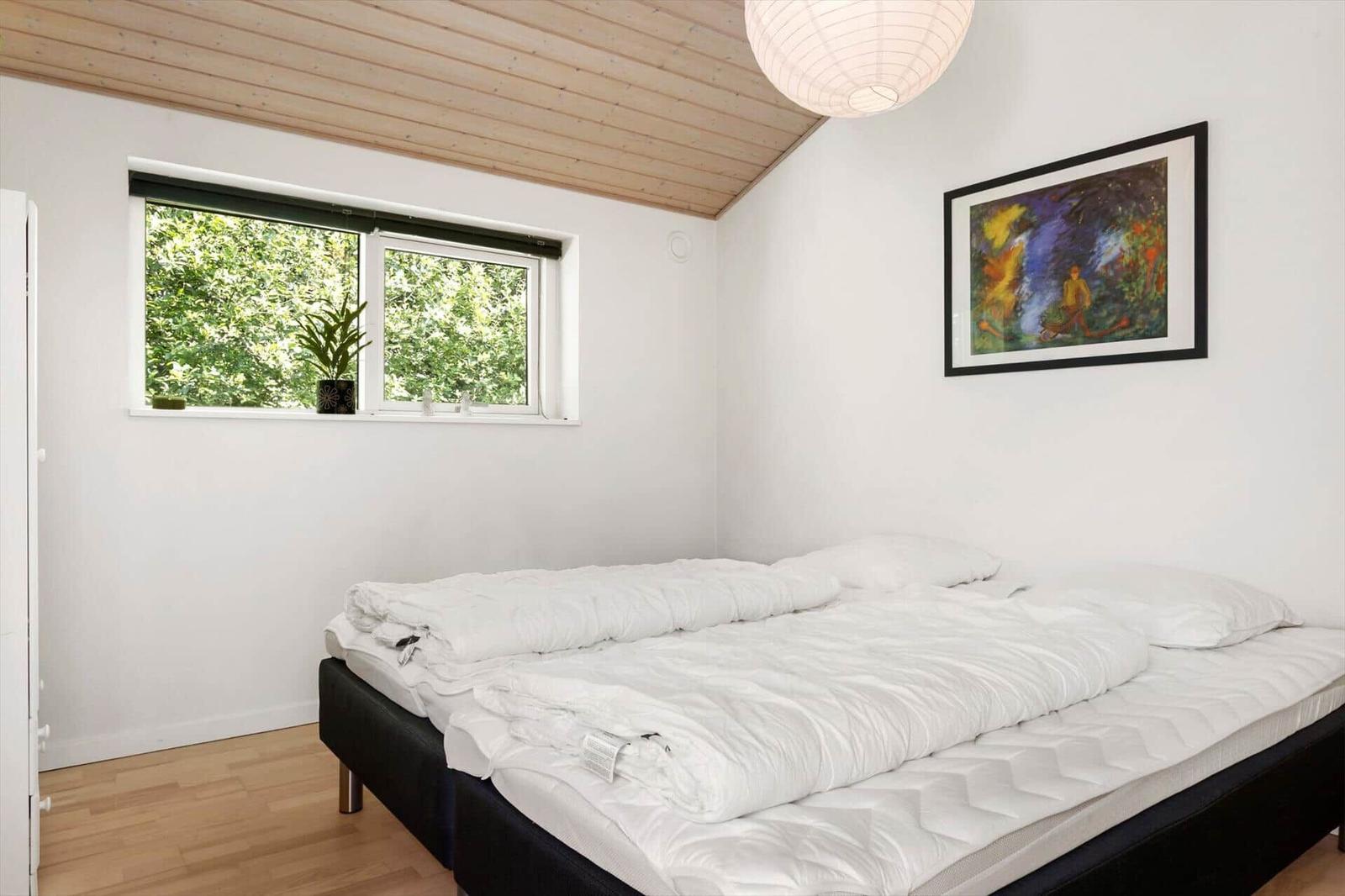 Schlafzimmer mit Bett, Fenster und Wandbild