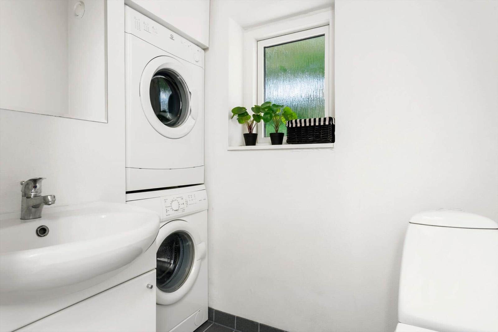 Waschmaschine und Trockner in einem Raum mit Waschbecken und Toilette.