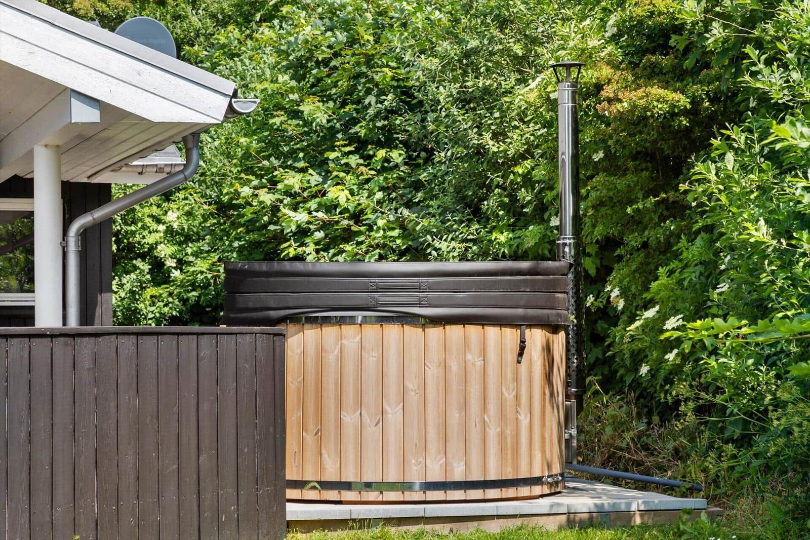 Hochwertiger Holzhot tub mit Edelstahlrohr auf Terrasse im Grünen.
