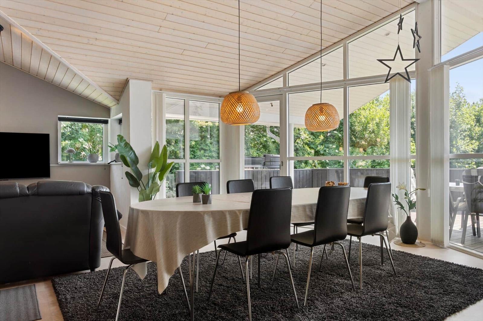 Essbereich mit Tisch, Stühlen und Blick auf Balkon. Decke mit Holzverkleidung und hängende Lampen.