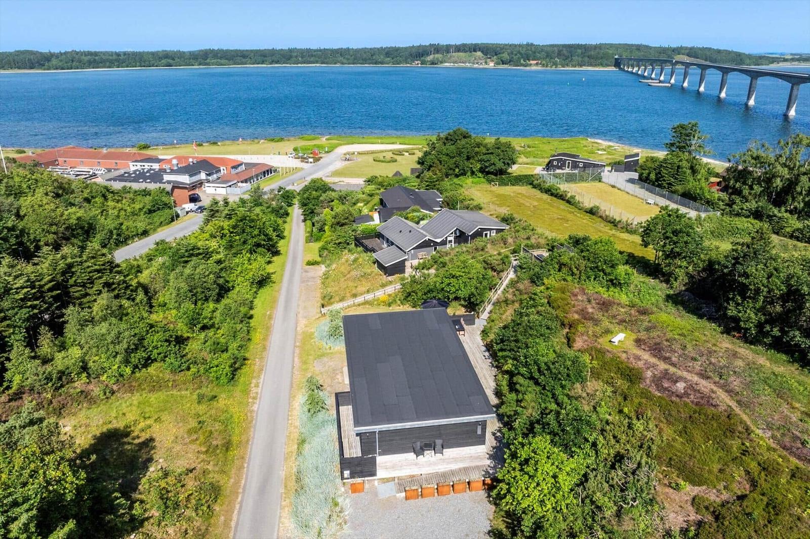Haus mit Blick auf See und Brücke, umgeben von Grünflächen und Bäumen.