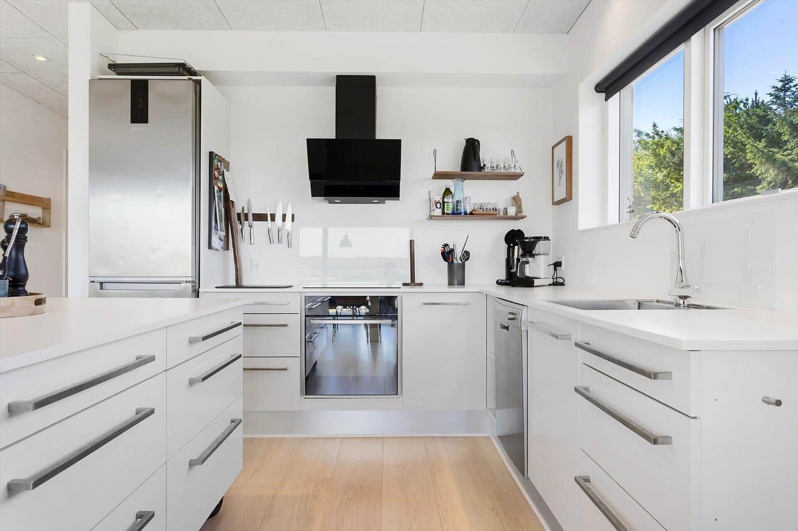 Moderne Küche mit weißen Schränken, Edelstahlgeräten und Holzboden.