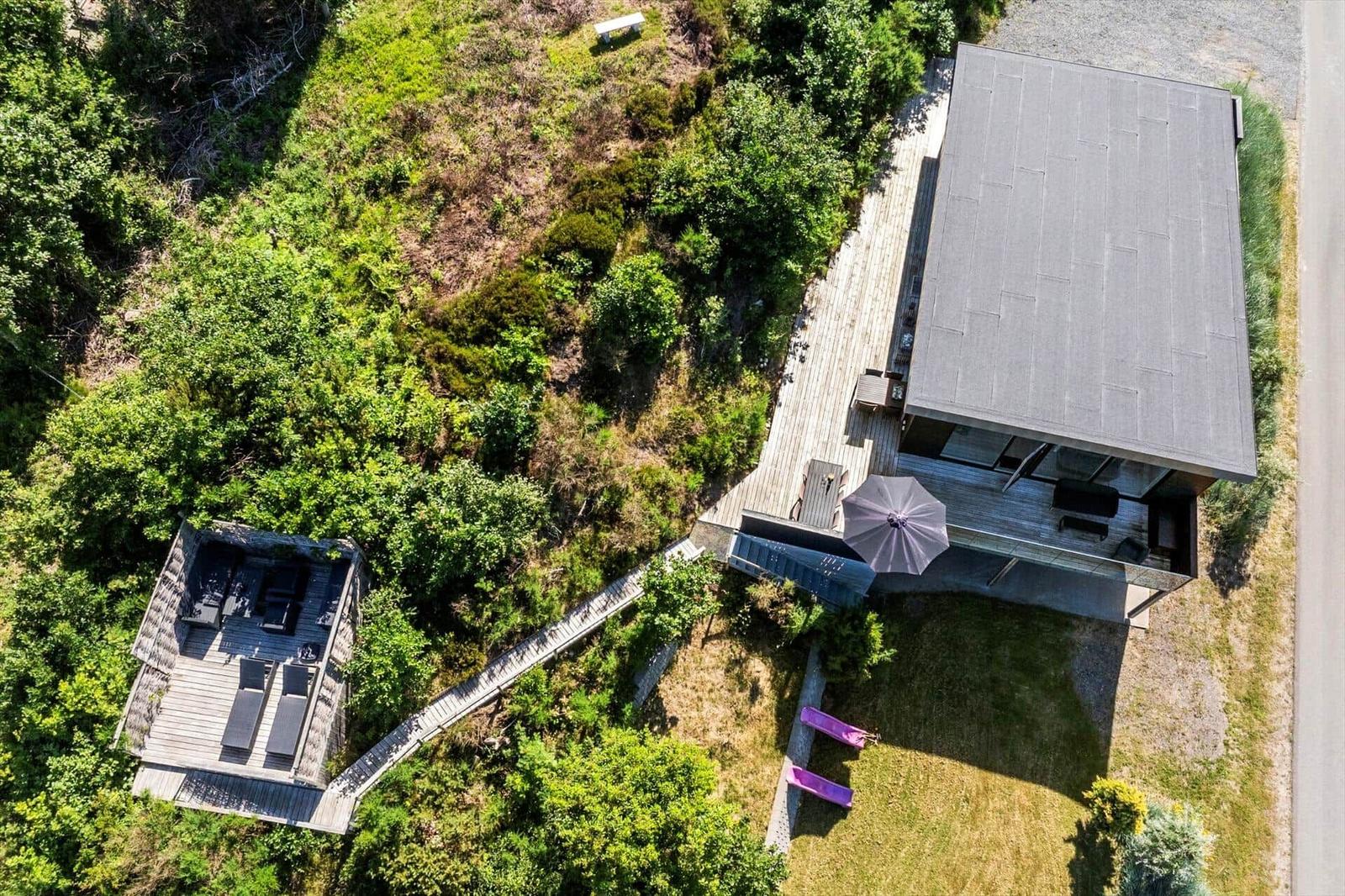 Moderne Villa mit Terrasse, Garten und Außendusche. Umgeben von Grünflächen und Wald.