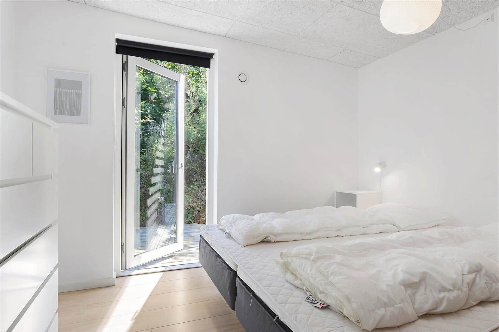 Schlafzimmer mit Bett, Schrank und Glastür zum Garten.