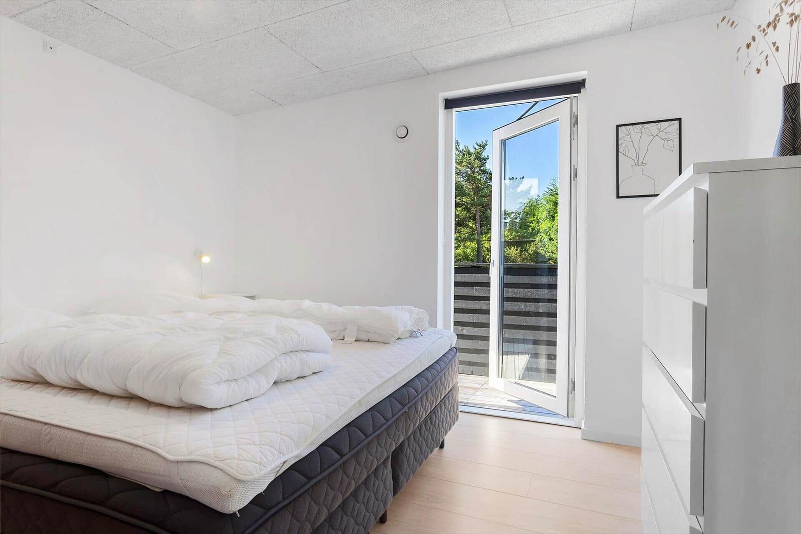 Schlafzimmer mit Bett, Schrank und Tür zum Balkon.