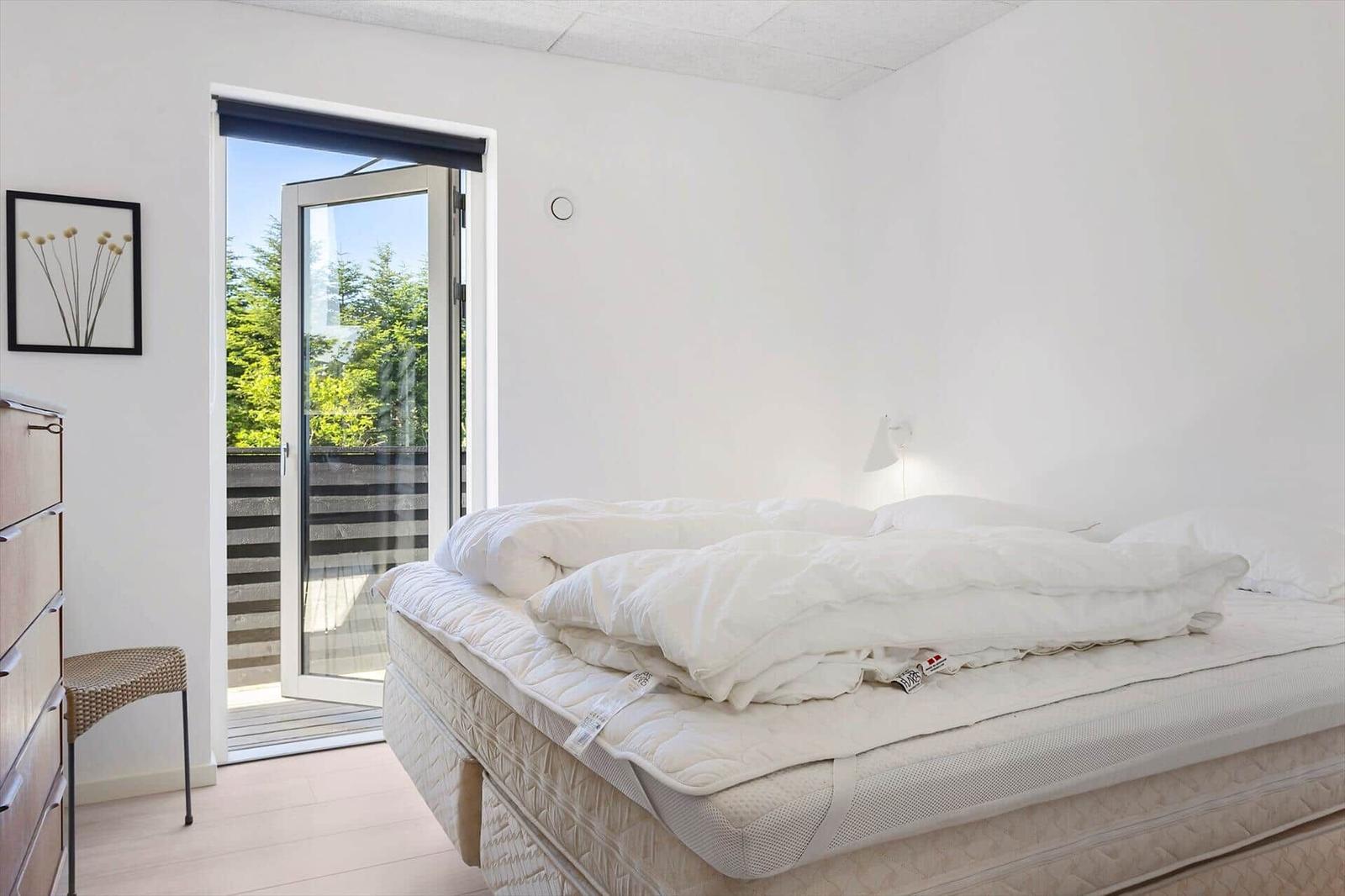 Schlafzimmer mit Bett, Schrank und Glastür zum Balkon.