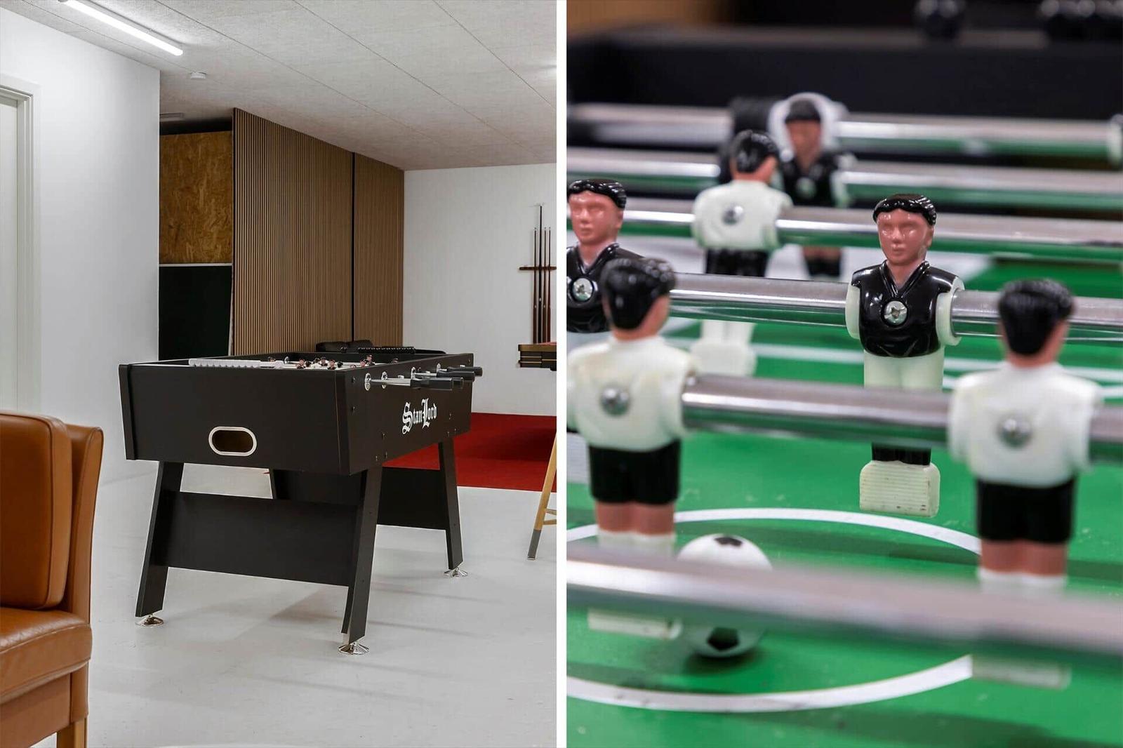 Fußballtisch mit Spielern und Kugel in einem Raum mit brauner Ledercouch.