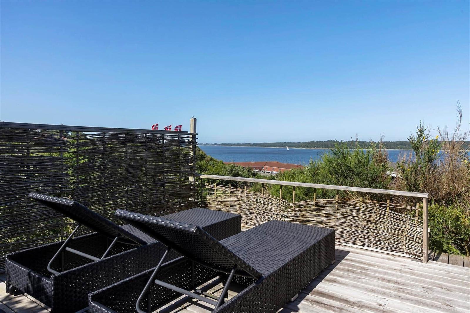 Terrasse mit Liegen und Blick aufs Wasser und Flaggen.