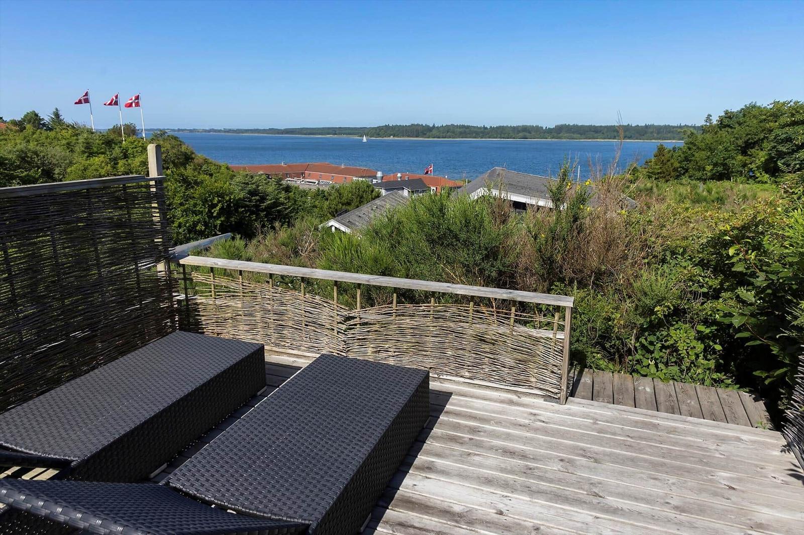 Terrasse mit Liegen und Blick auf See und Flaggen.