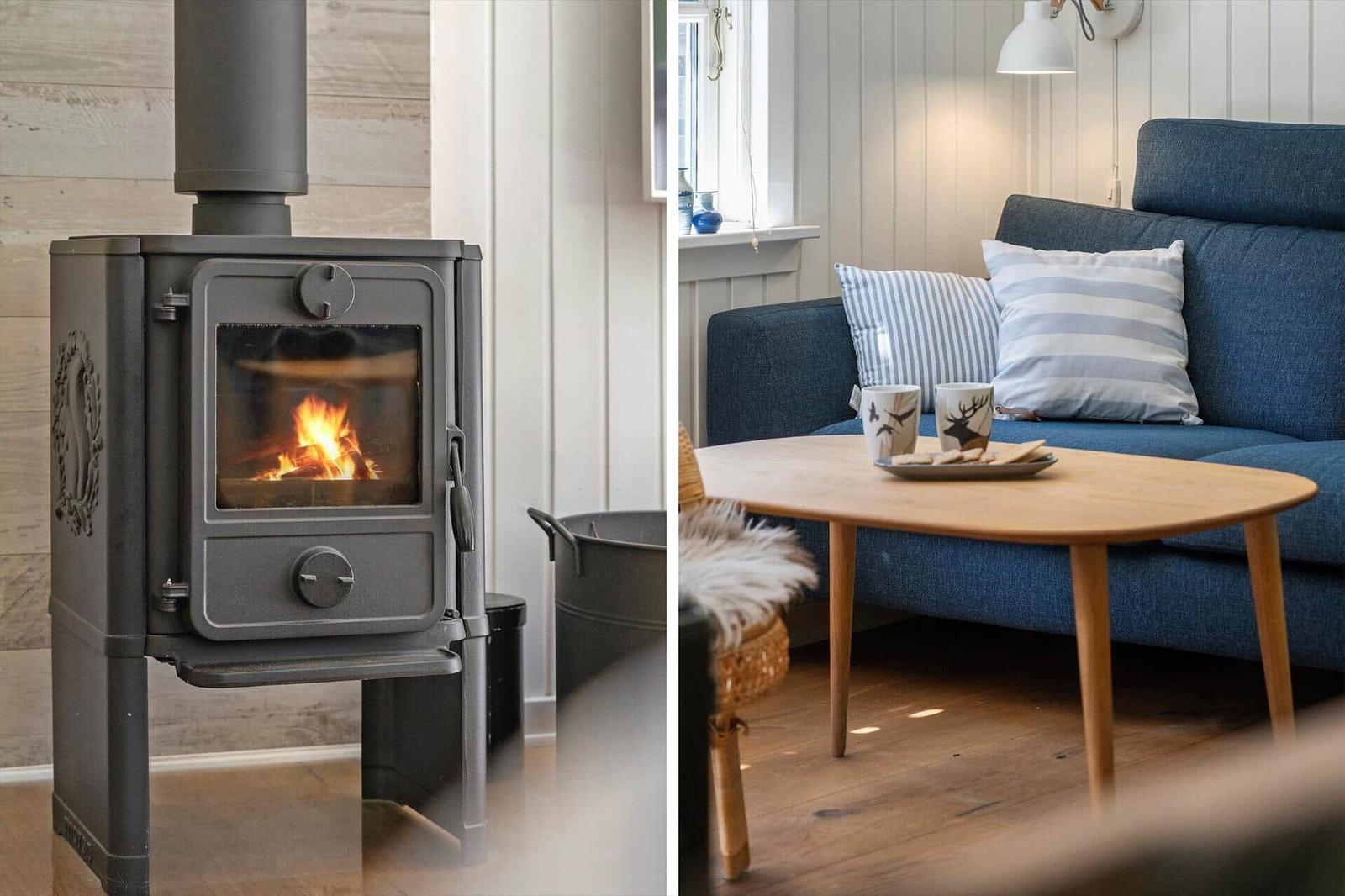 Kaminofen mit brennendem Feuer und blauer Couch mit Kissen und Tisch.