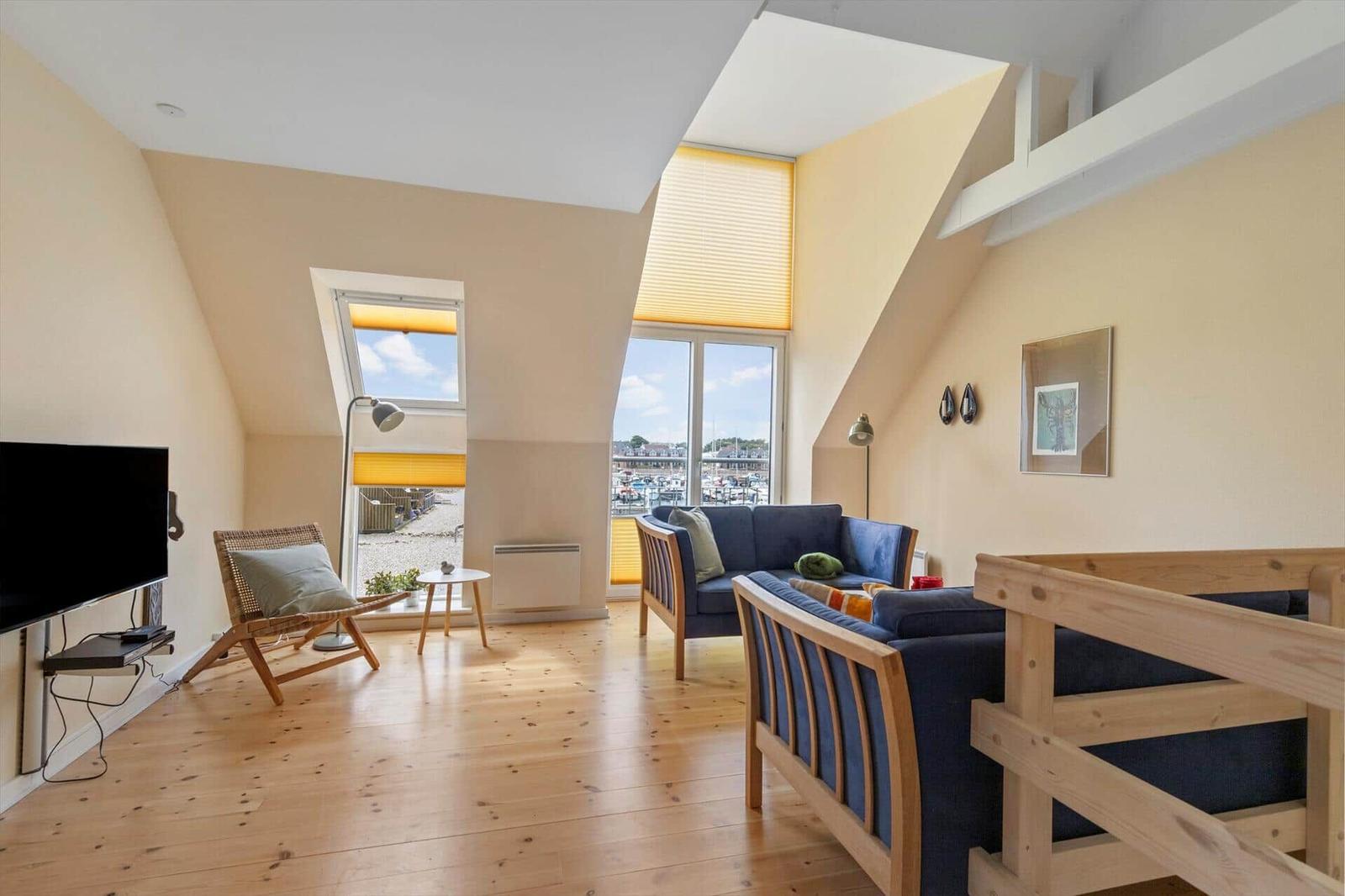 Wohnzimmer mit Holzboden, Sofa und Blick auf Hafen