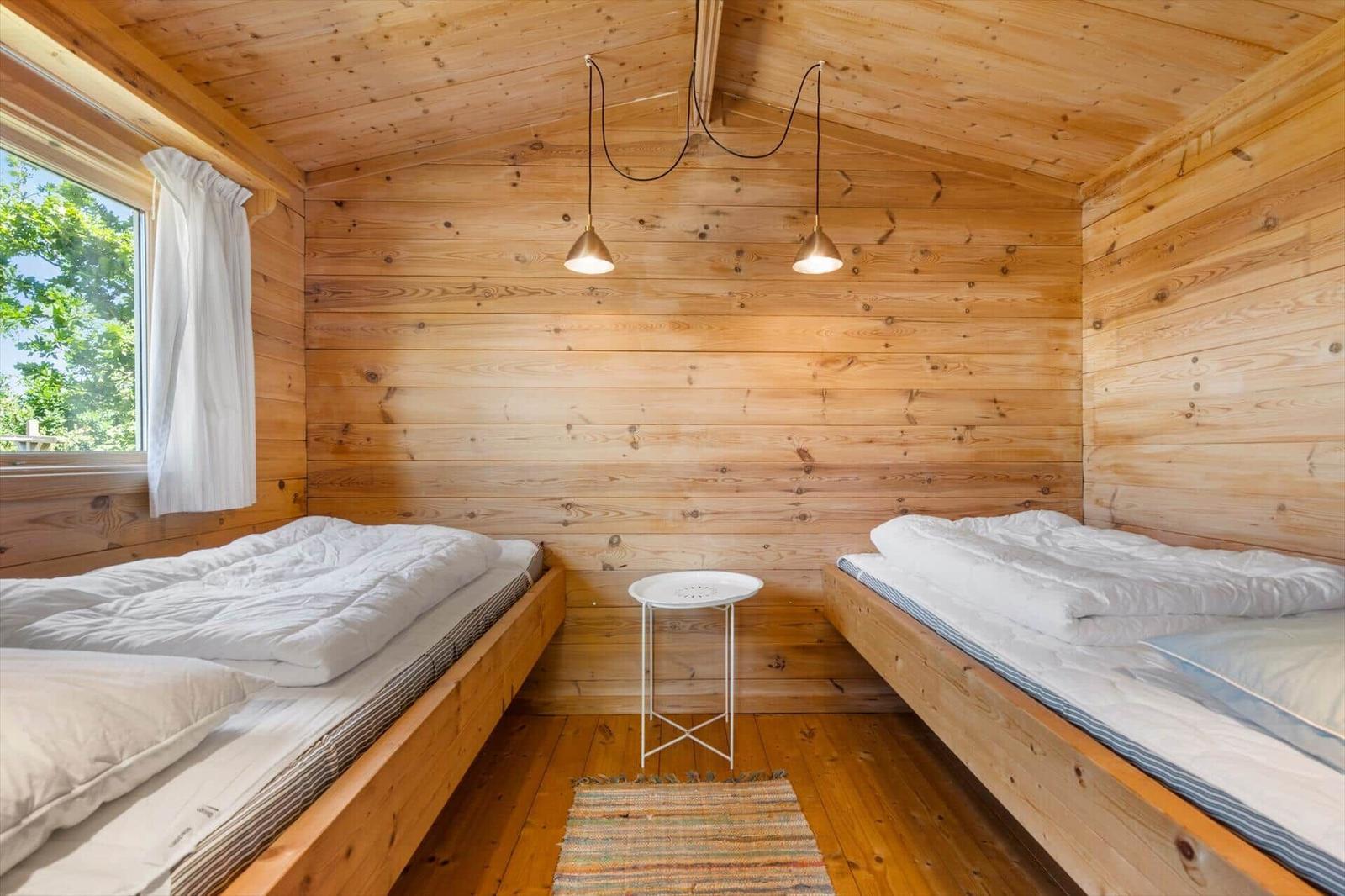 Zwei Betten in einem Holzhaus mit Fenster und Tisch