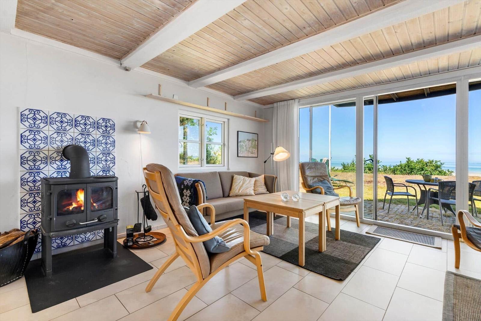 Wohnzimmer mit Kamin, Sofa und Blick aufs Meer.