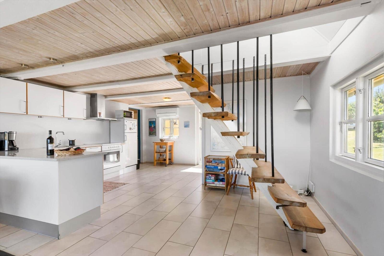 Küche mit Essbereich und Holztreppe zur oberen Etage.