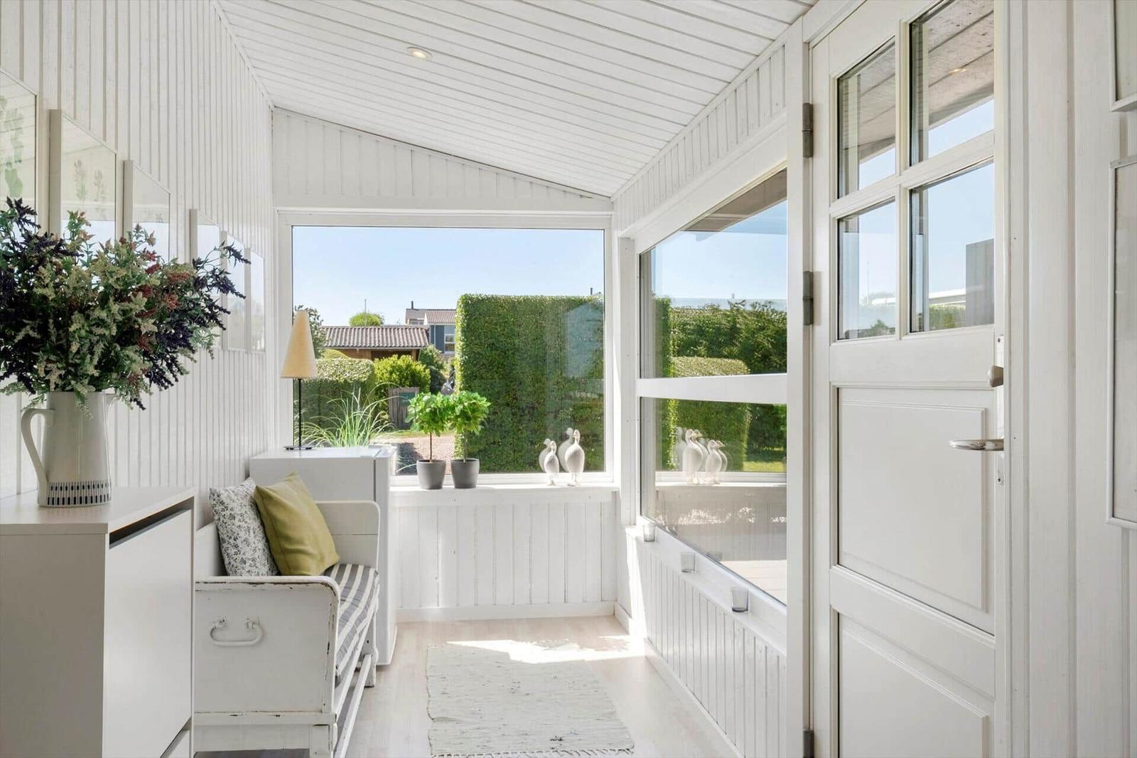A white interior space with a view of a green garden and a door.