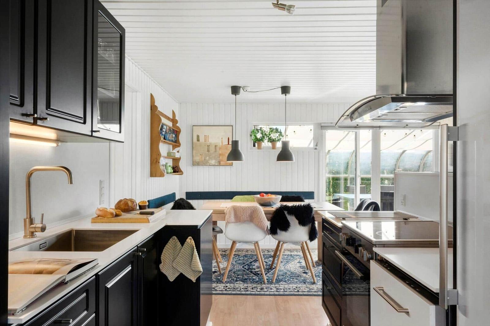 Kitchen with dining area, black cabinets, wooden chairs, and window to terrace.