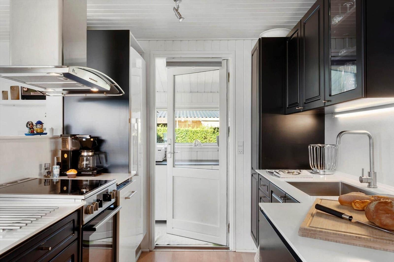 Kitchen with black cabinets, white countertop, and door to the garden.