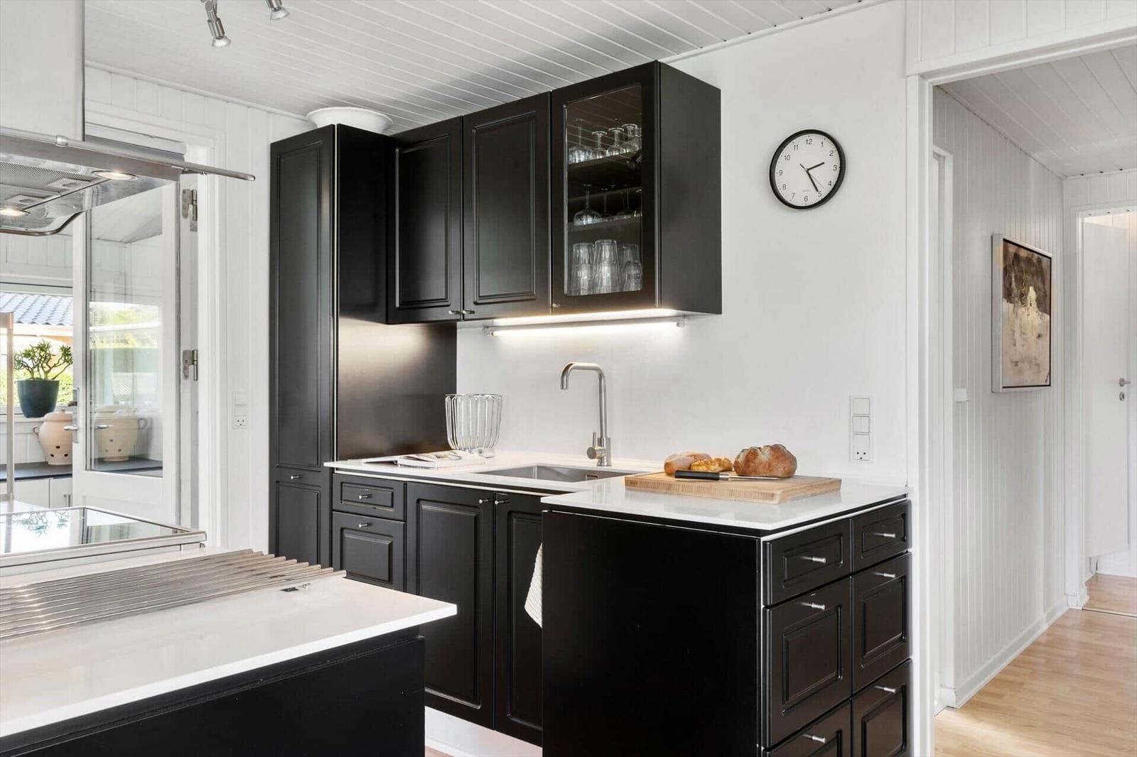 Kitchen with black cabinets, white countertop, and integrated sink.