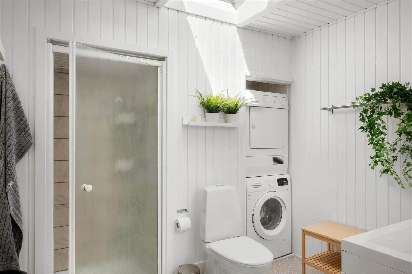 Bathroom with shower, toilet, washing machine, and dryer.