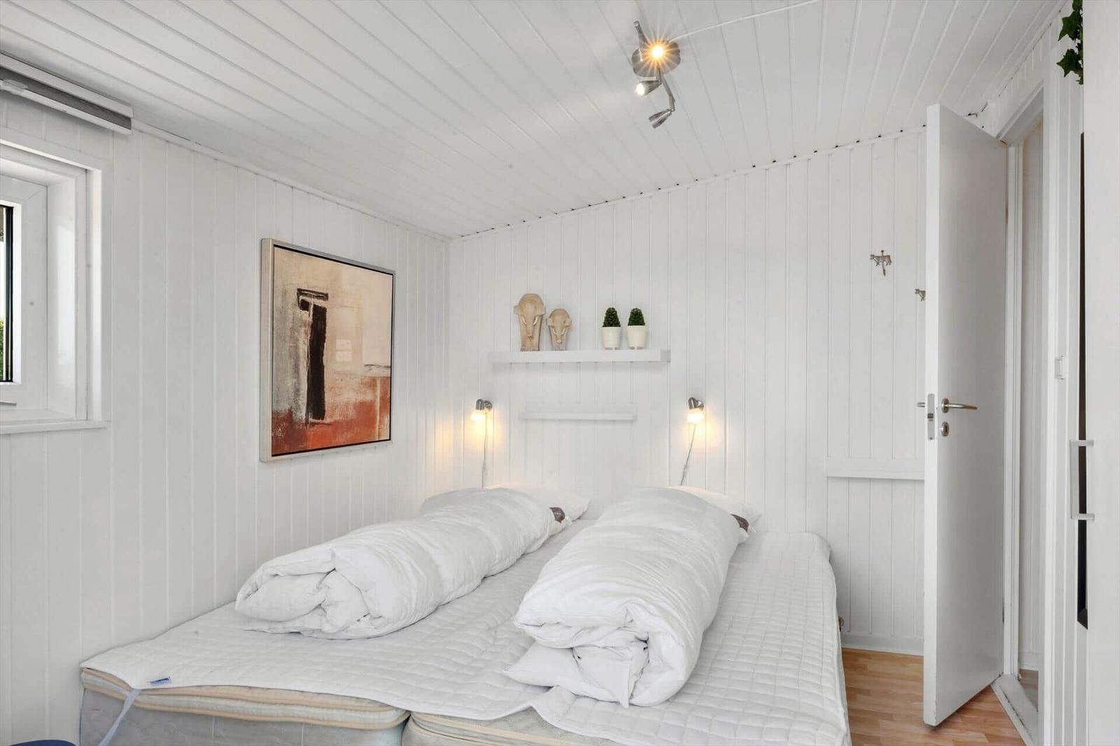 Two beds with white bedding in a room with white walls and ceiling.