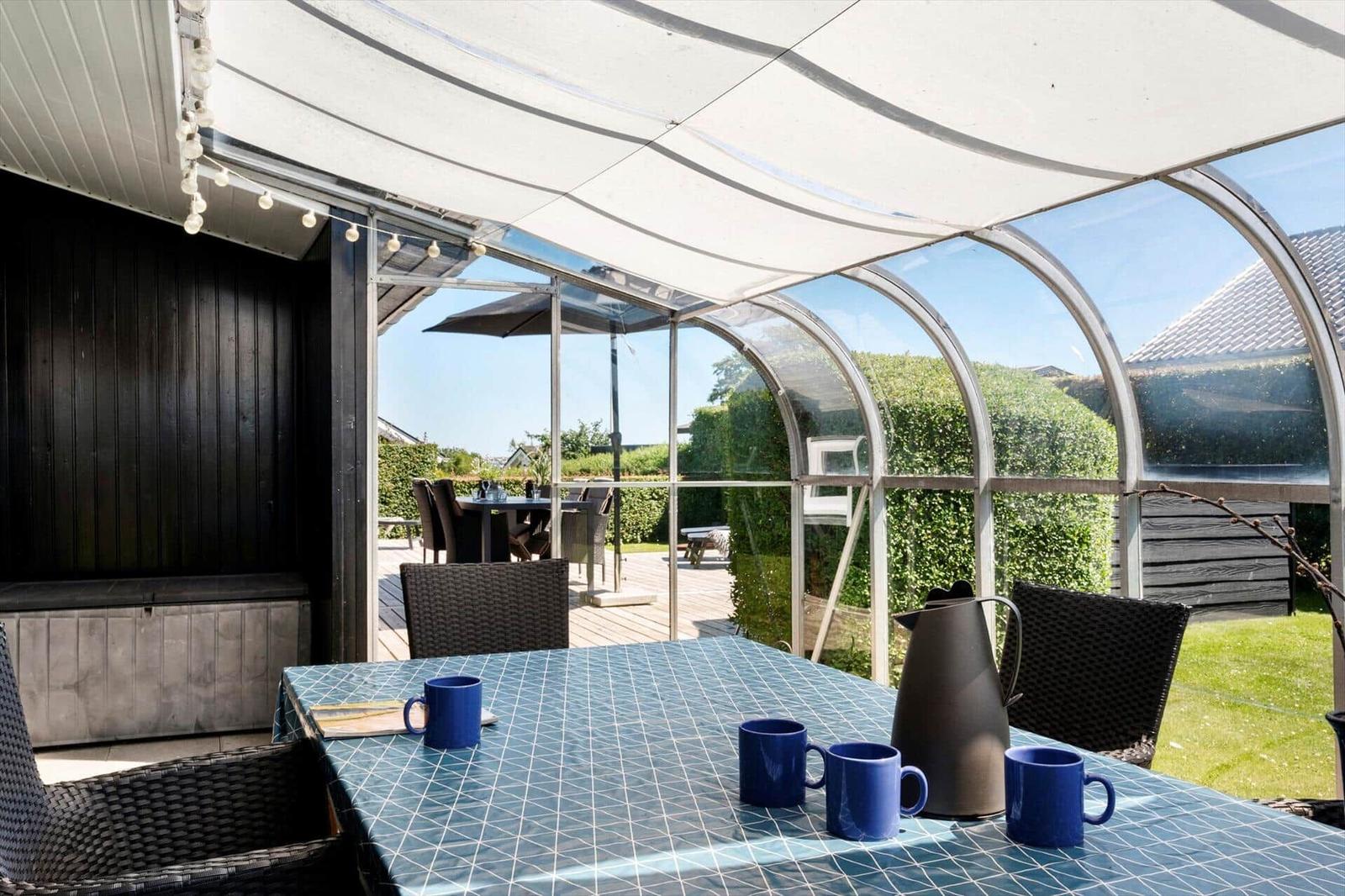 Terrace with table, chairs, and sun cover. View of garden and neighboring houses.