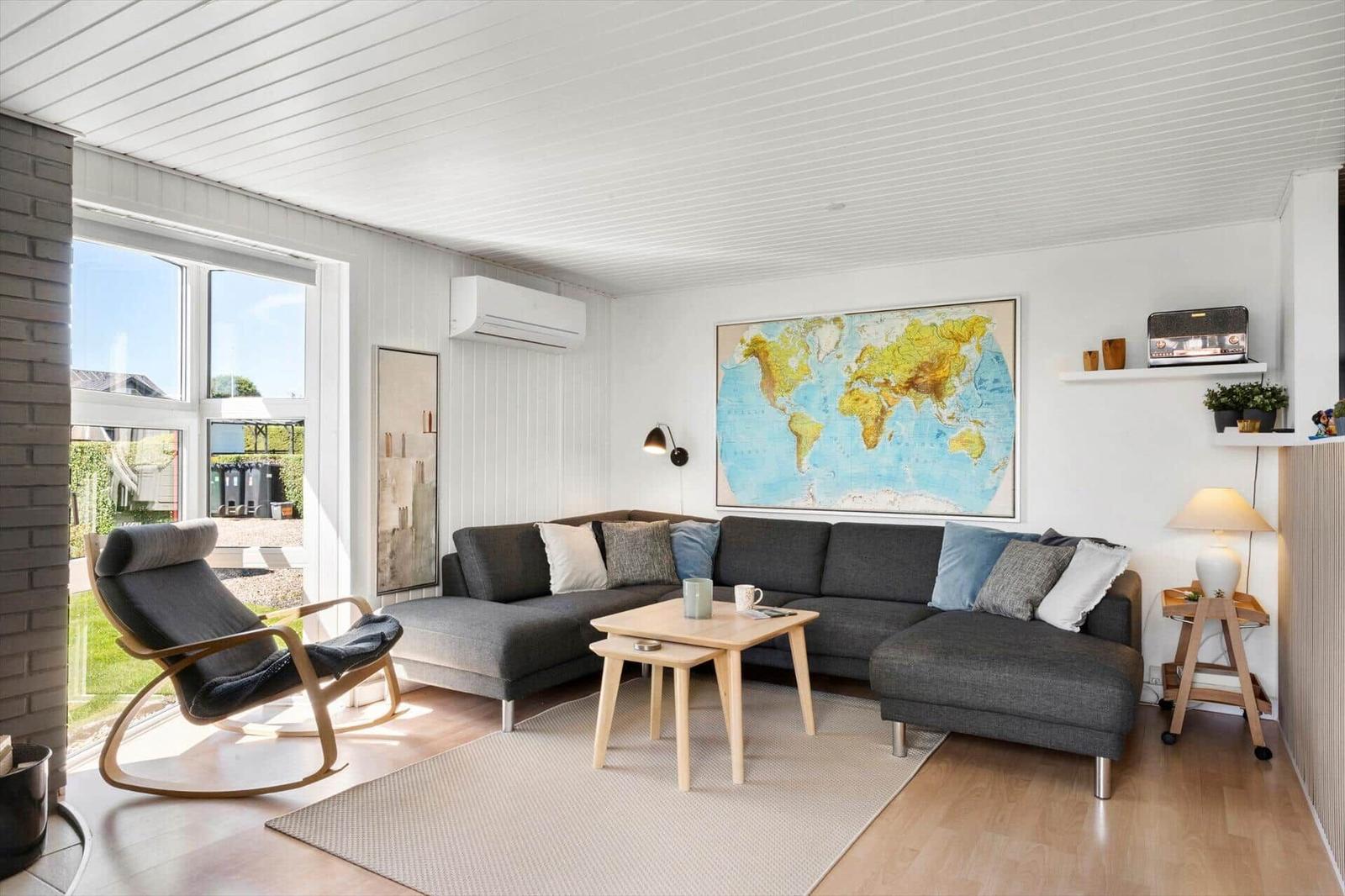 Living room with gray sofa, wooden table, and world map on the wall.