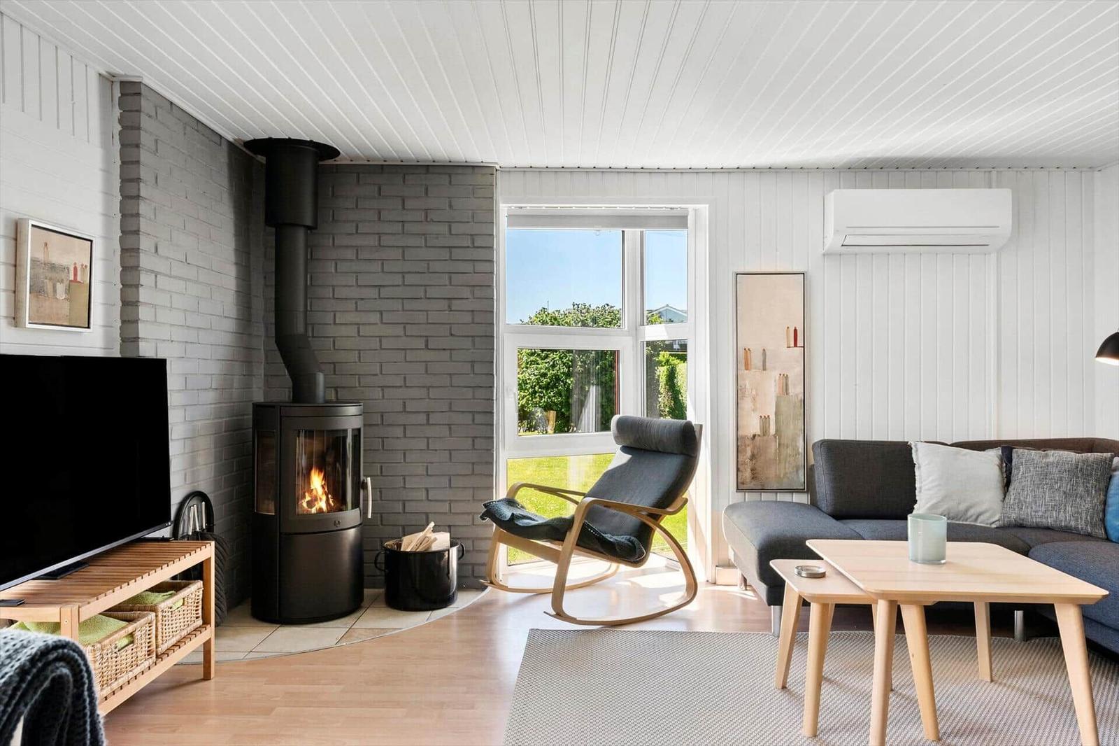 Living room with fireplace, sofa, chair, and window to the garden.