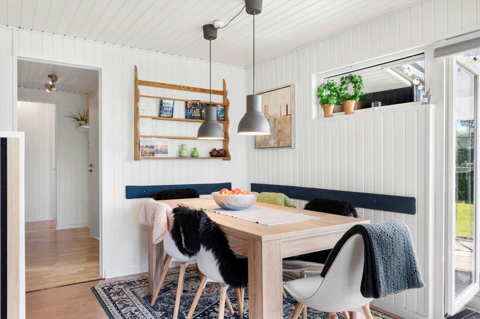 Dining area with wooden table, bench, and pendant lights on white walls.