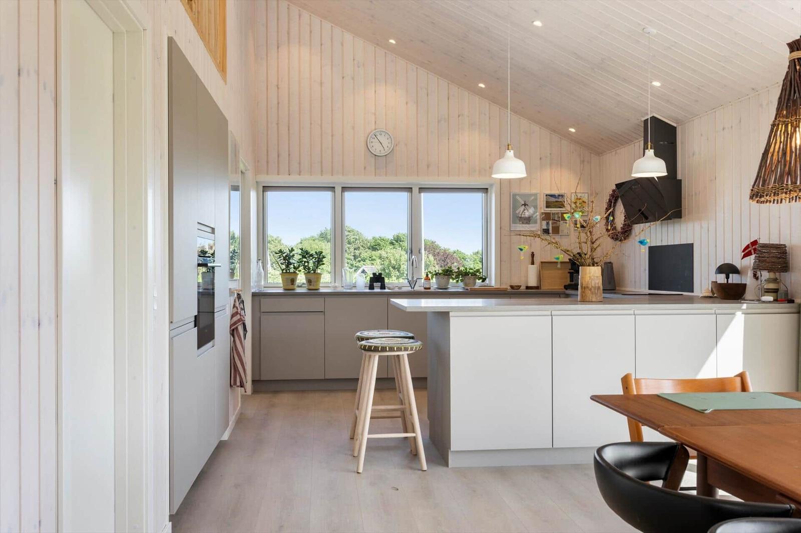 Küche mit Holzwand, Fenster, Arbeitsplatte und Sitzgelegenheit.