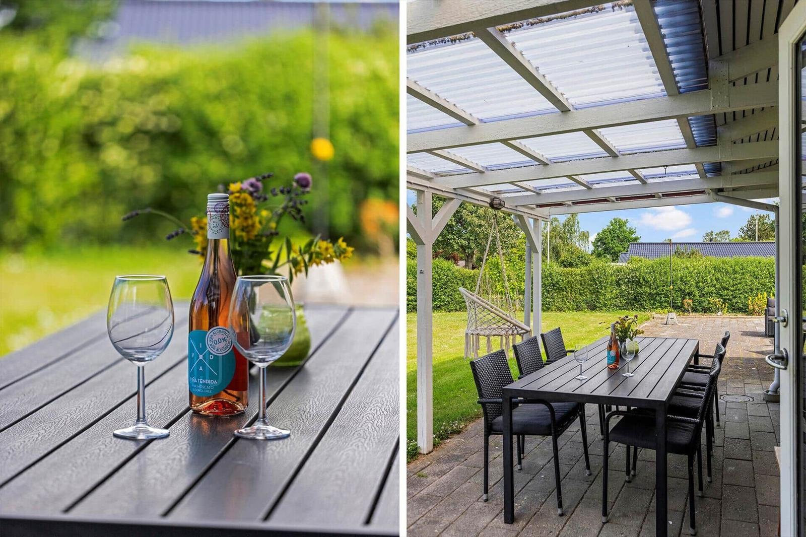 Tisch mit Weinflasche und Gläsern im Garten unter Pavillon mit Schaukel.