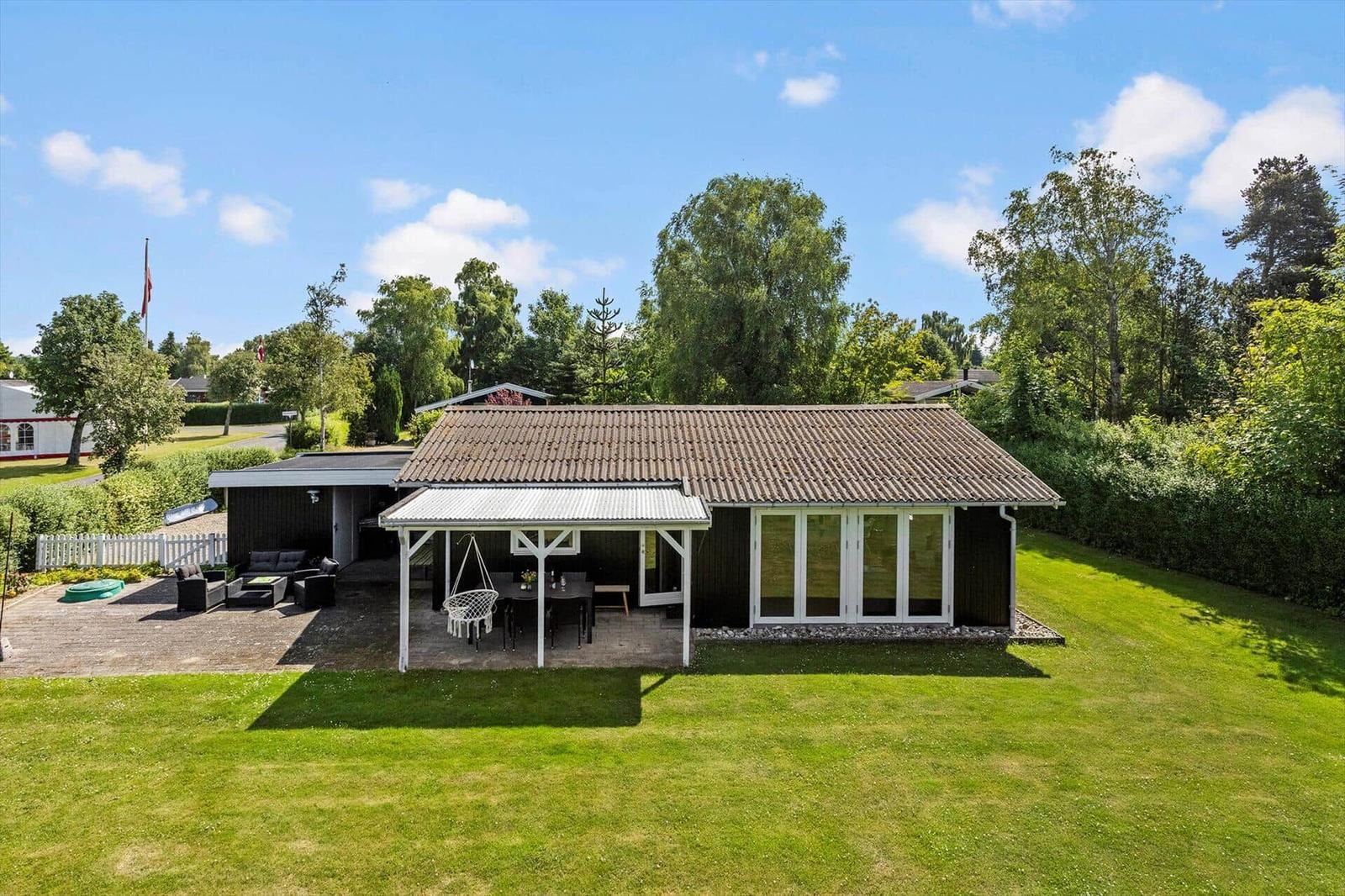 Ein Haus mit Terrasse, Garten und Sitzgelegenheiten unter freiem Himmel.
