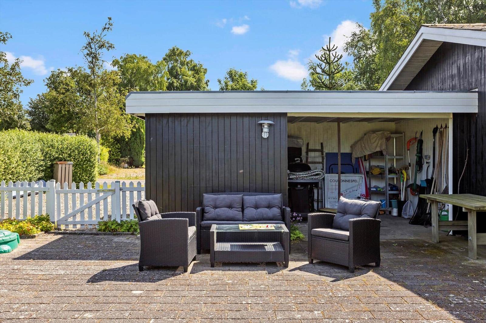Außenbereich mit Sitzgruppe unter Pavillon. Garage und Gartenbereich sichtbar.