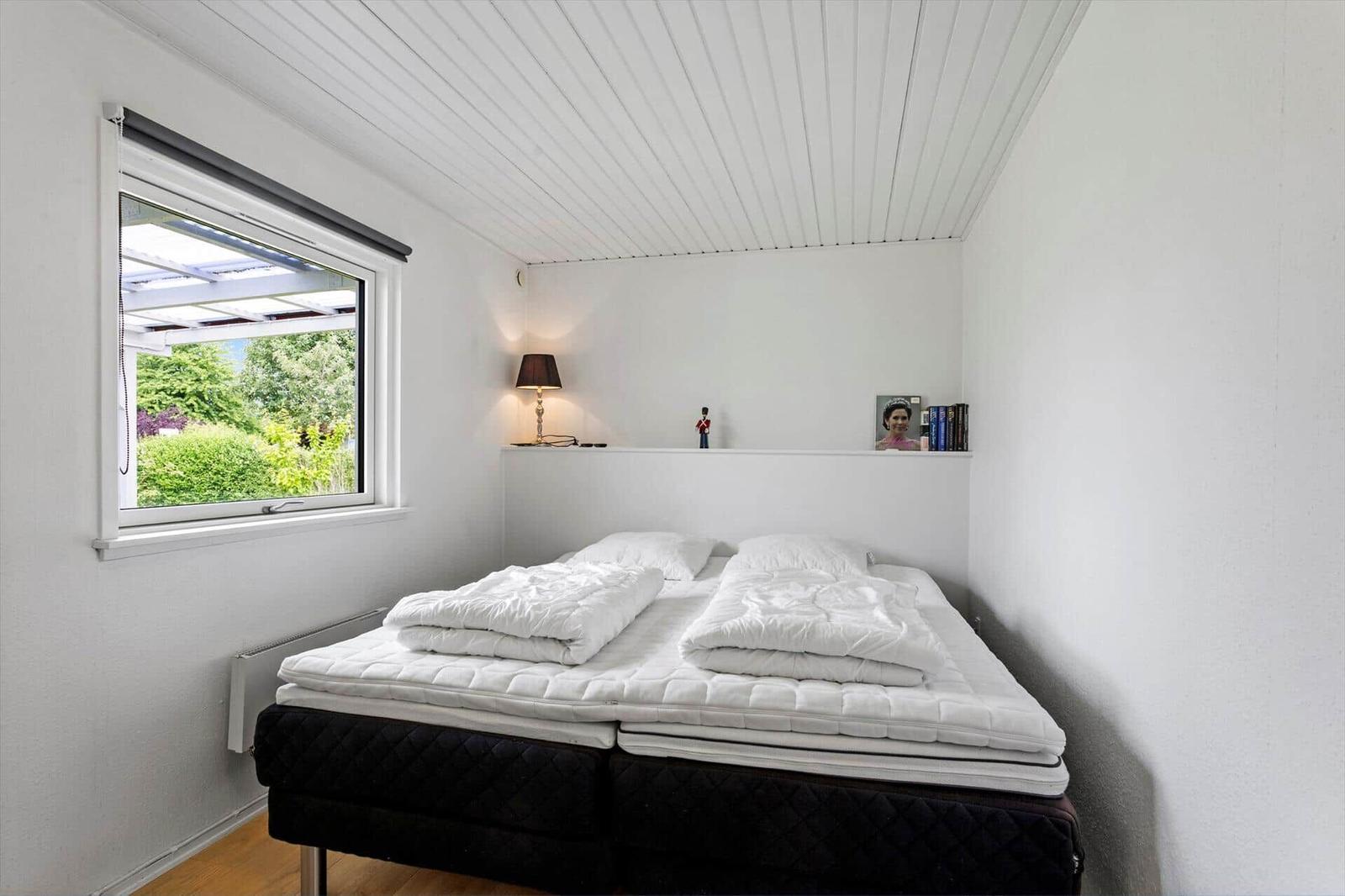 Schlafzimmer mit Doppelbett, Fenster und Regal