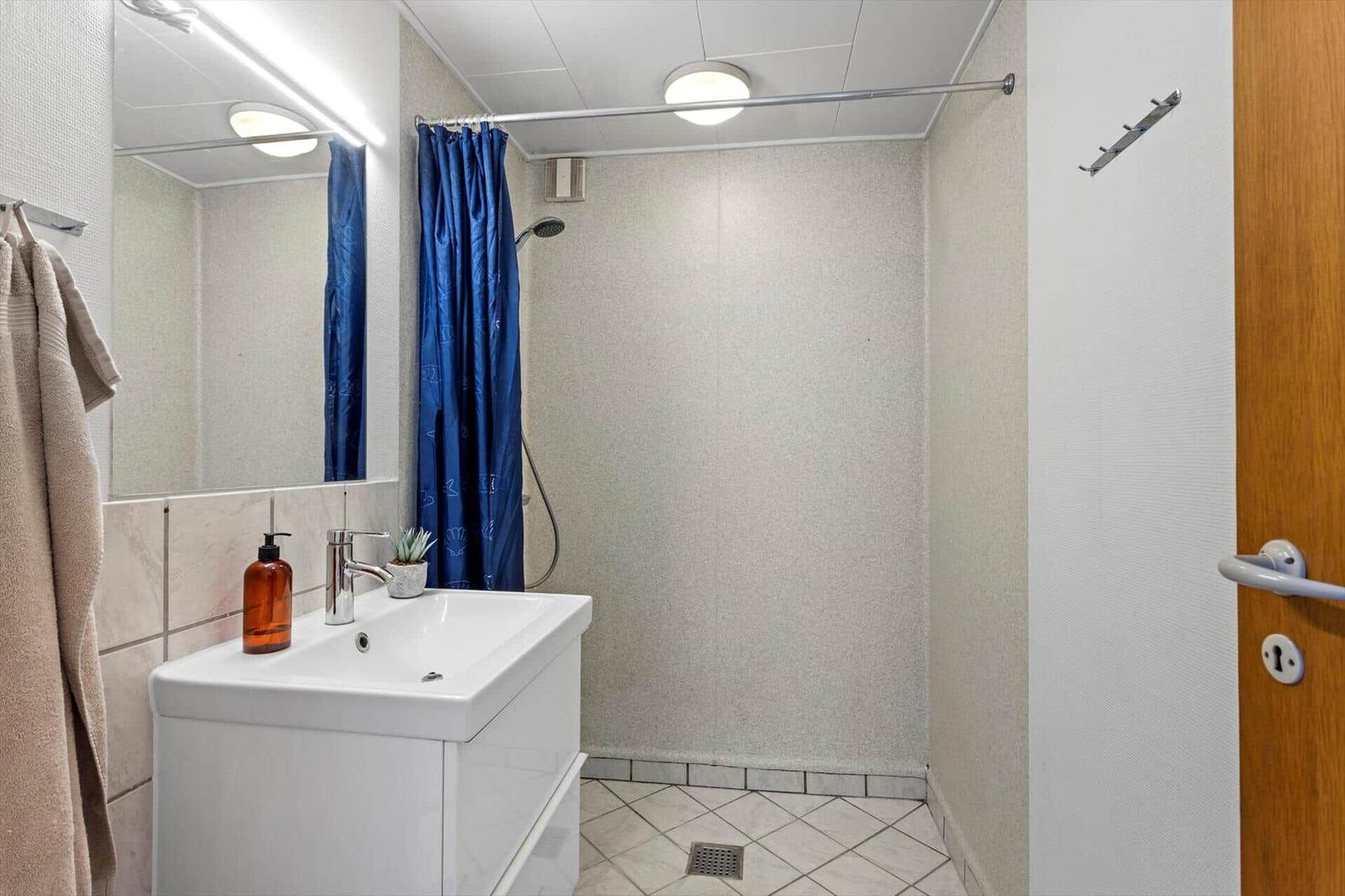 Badezimmer mit Dusche, Waschbecken und Spiegel