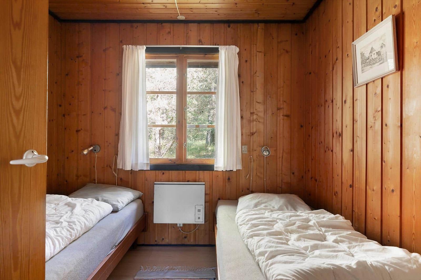 Zwei Betten in einem Zimmer mit Holzwänden und Fenster.