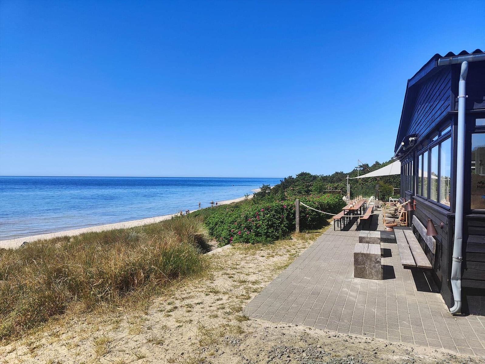 Strandnahe Terrasse mit Sitzgelegenheiten und Blick aufs Meer.