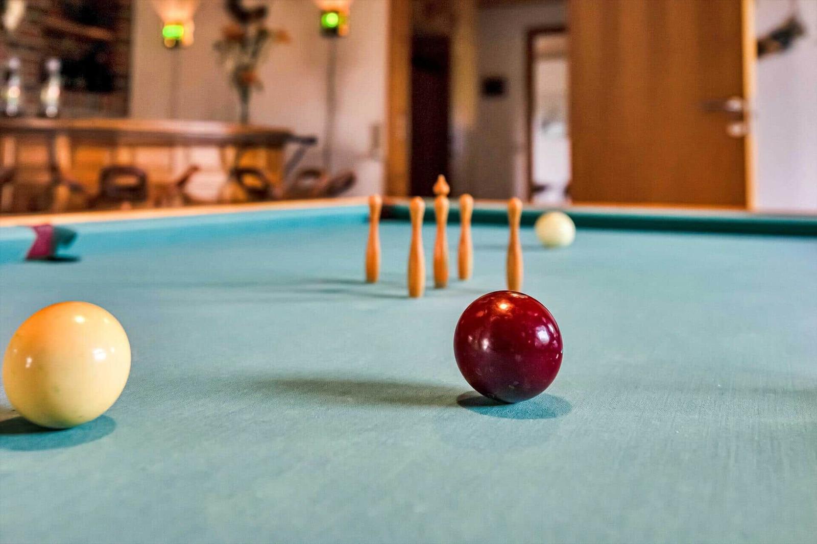 Billiard table with balls and bowling pins on green felt