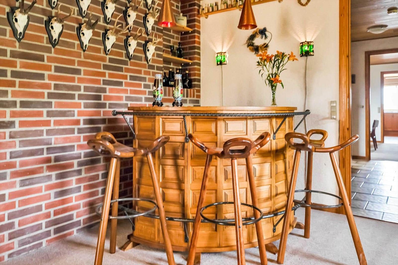Wooden bar with three stools in front of brick wall with deer heads